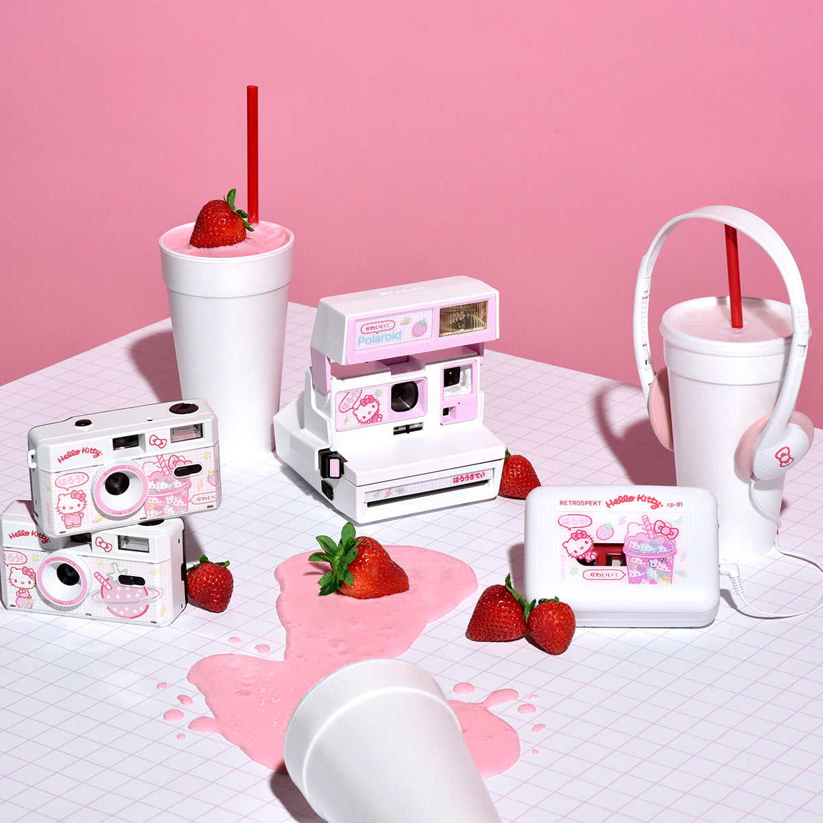 Hello Kitty Strawberry Kawaii collection on display in front of a pink background, surrounded by strawberries and a pink milkshake.